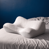 Oreiller cervical ergonomique DEENII en mousse à mémoire de forme posé sur un lit